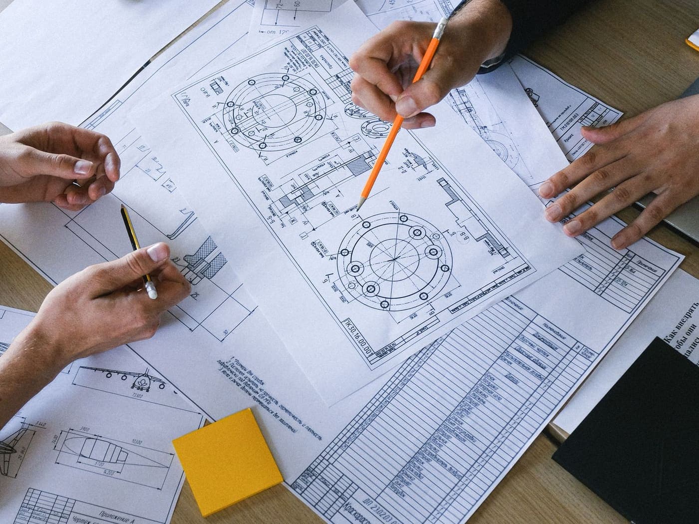 Engineers working over technical drawings on a table